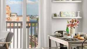 A modern dining area with a view of a beach and cityscape through large sliding doors. - 9 Bedrooms-7 Bath-2 Kitchens-Parking-Sleeps 22! (San Diego)