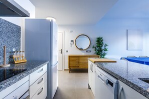 Una cocina moderna con encimeras de granito, horno empotrado y un armario de madera.