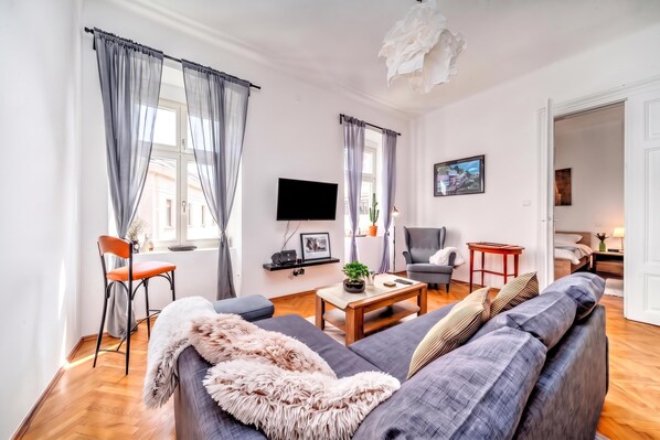 A modern living room with a sofa, a television, a coffee table, and a chair. - City Soul Apartment (Zagreb)