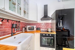 Una cocina con un lavabo blanco, un microondas, un horno y una estufa.