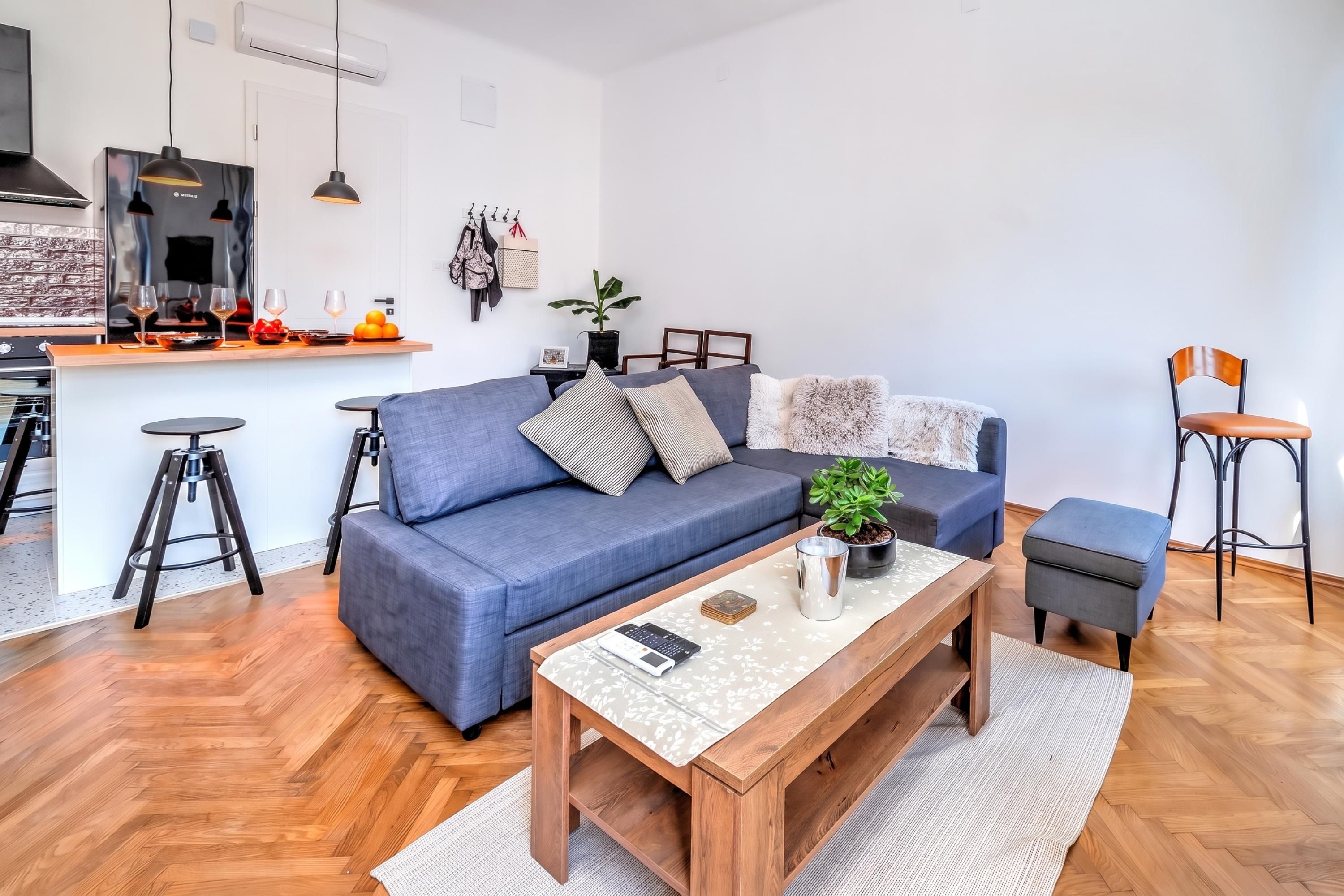 Un salon moderne avec un canapé, une table basse et des tabourets de bar.