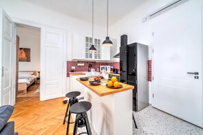 A modern kitchen with a central island, bar stools, and a dining area with a sofa.