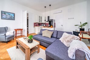 Una sala de estar moderna con un sofá gris, una mesa de centro de madera con una planta y un sillón gris.