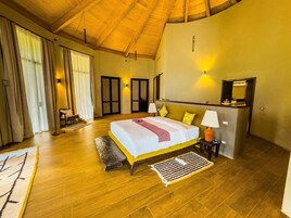 Un dormitorio amplio con una cama grande, suelo de madera y techo alto.