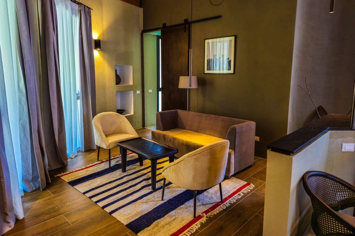 A modern living room with a sofa, armchair, and coffee table. There is a wooden floor and a striped rug.