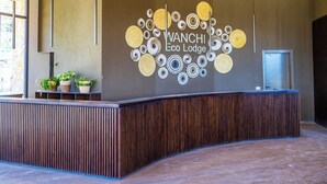 Un mostrador de recepción de diseño moderno, techo de madera y pared con un motivo circular y el texto "WANCHI Eco Lodge".