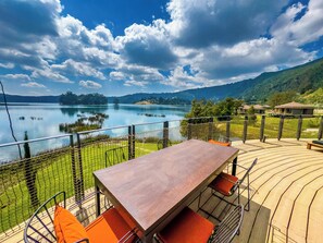 A wooden deck with a table and chairs overlooking a lake with a mountainous backdrop. - Wanchi Ija Eco Lodge by Ethiopian Skylight (Shube)