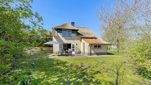 A two-story house with a thatched roof and a small attached shed.