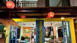 A brightly lit interior with a central seating area, open doors leading to another room, and a balcony with a railing. - Pearl Beach Homestay (Da Nang)