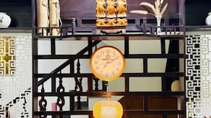 A room with a wooden cabinet, a clock, and decorative items. - Pearl Beach Homestay (Da Nang)