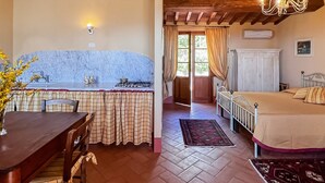 A cozy room with a kitchen area, a dining table, and a bed. - Country House in Touscany ID 4161 (Buti)