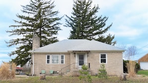 A two-story house with a stone facade, a front porch, and a small front yard. - Acreage Near Downtown (Indianapolis)