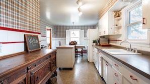 A kitchen with a wooden cabinet, a white refrigerator, and a window. - Acreage Near Downtown (Indianapolis)