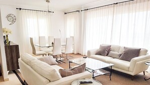 Un salon moderne comprenant un canapé, des fauteuils, une table basse et un coin repas avec des chaises et une table.