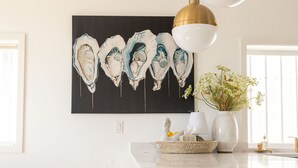 A modern kitchen with a marble countertop, gold accents, and a black and white artwork above the island. - The Ressa 2BED/1BATH Located in the heart of Downtown (Sitka)