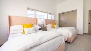 A hotel room with two beds, each with white bedding and yellow pillows, a nightstand, a window with a view, and a door. - The Ressa 2BED/1BATH Located in the heart of Downtown (Sitka)