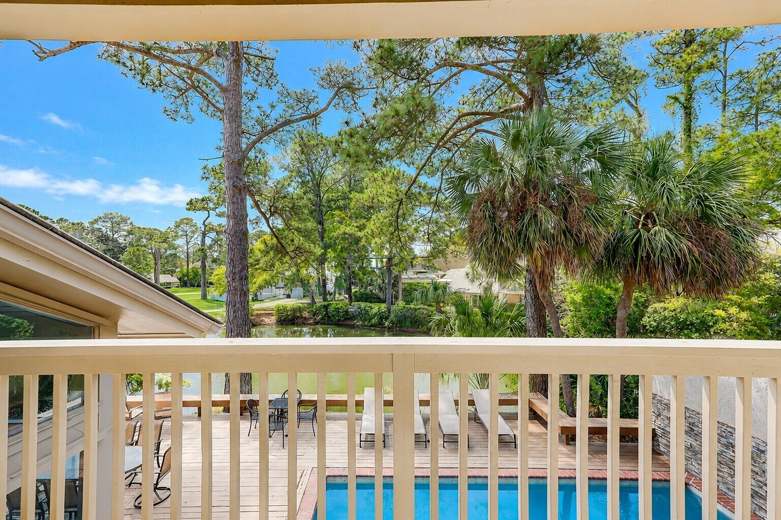 A pool area with a wooden deck, lounge chairs, and a view of the surrounding landscape.