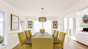 Une salle à manger avec une longue table, six chaises et un lustre.