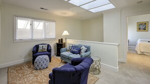 A spacious living room with a high ceiling and skylights, a cozy seating area with a sofa and chairs, and a staircase leading to another room. - 30 Windjammer - Take in the Back Nine Views of Harbour Town Golf Links (Hilton Head Island)