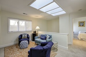A spacious living room with a high ceiling and skylights, a cozy seating area with a sofa and chairs, and a staircase leading to another room. - 30 Windjammer - Take in the Back Nine Views of Harbour Town Golf Links (Hilton Head Island)