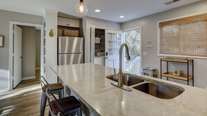 A modern kitchen with a large island, stainless steel appliances, and a window with blinds. - 78 Dune Lane - 2nd Row Ocean Home in NFB with Backyard Entertainment! (Hilton Head Island)