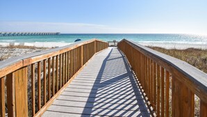 A wooden boardwalk leading to the beach with a pier in the background. - Gulf Front 3/3 Resort w/Pool & 2 King Suites. Chair/umbrella set-up included! (Navarre)