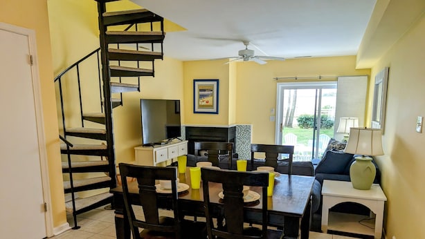 Un comedor con una escalera espiral, chimenea y vistas al exterior.