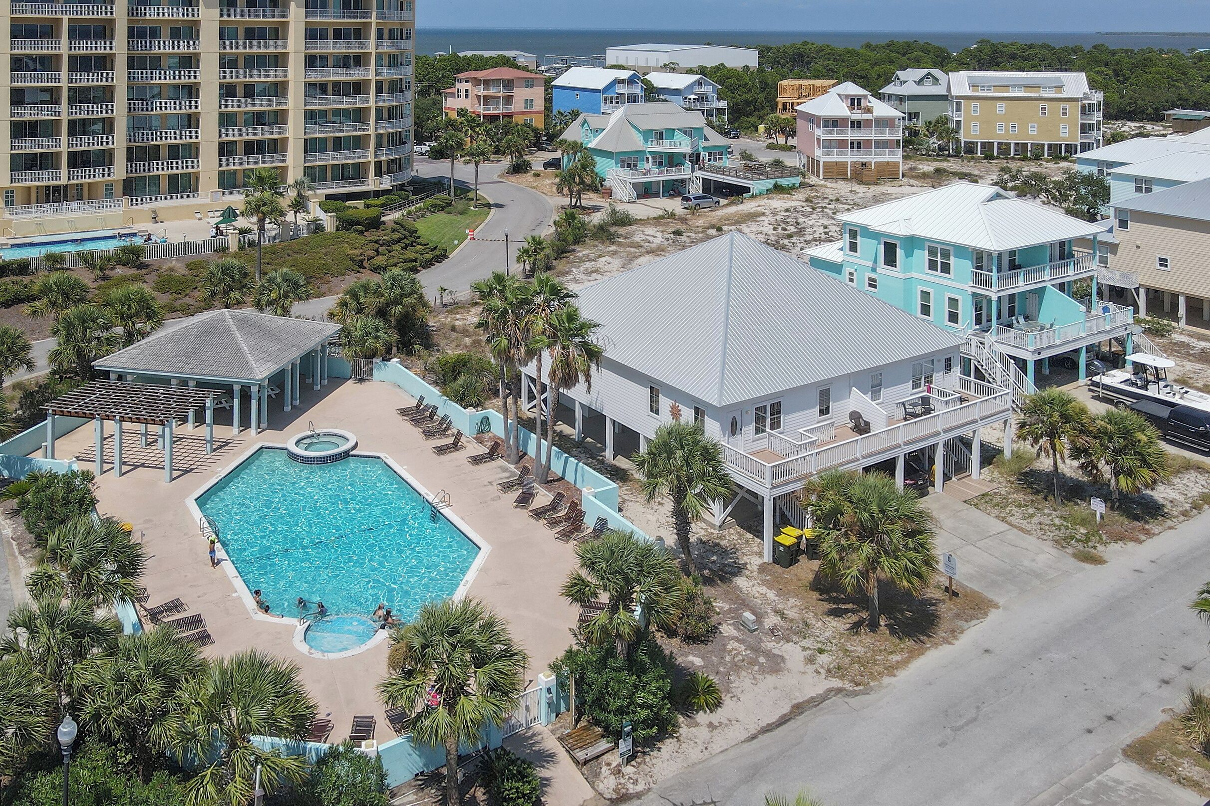 Vue aérienne d’un complexe hôtelier comprenant une piscine, des propriétés situées en bord de mer et un grand hôtel.