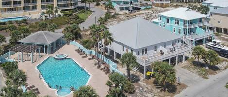 Vue aérienne d’un complexe hôtelier comprenant une piscine, des propriétés situées en bord de mer et un grand hôtel.