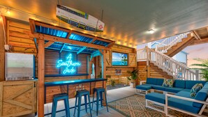A cozy bar area with a neon sign, wooden bar stools, and a staircase leading to an upper level. - Exquisite Beach Retreat You Won't Want To Miss! Pet-Friendly (Port Aransas)