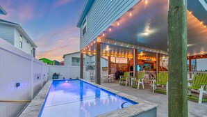 A swimming pool with a covered patio area, outdoor seating, and string lights. - Exquisite Beach Retreat You Won't Want To Miss! Pet-Friendly (Port Aransas)