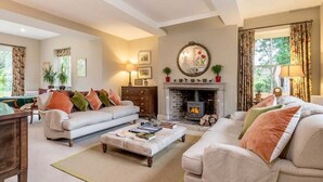 A cozy living room with a fireplace, two sofas, a coffee table, and a dining area with a table and chairs. - Monnington House & Cottages Sleeps 24 12 beds & 12 baths nr Hereford &Hay on Wye (Hereford)
