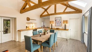 A spacious kitchen with wooden beams, a dining area with teal chairs, and a large window. - Monnington House & Cottages Sleeps 24 12 beds & 12 baths nr Hereford &Hay on Wye (Hereford)