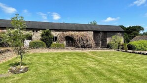 A stone building with a dark roof, surrounded by a well-maintained lawn and small trees. - Monnington House & Cottages Sleeps 24 12 beds & 12 baths nr Hereford &Hay on Wye (Hereford)