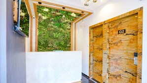 A reception area with a green wall, a wooden door labeled G2, and a marble floor. - Hotel Gorrion (Mumbai)
