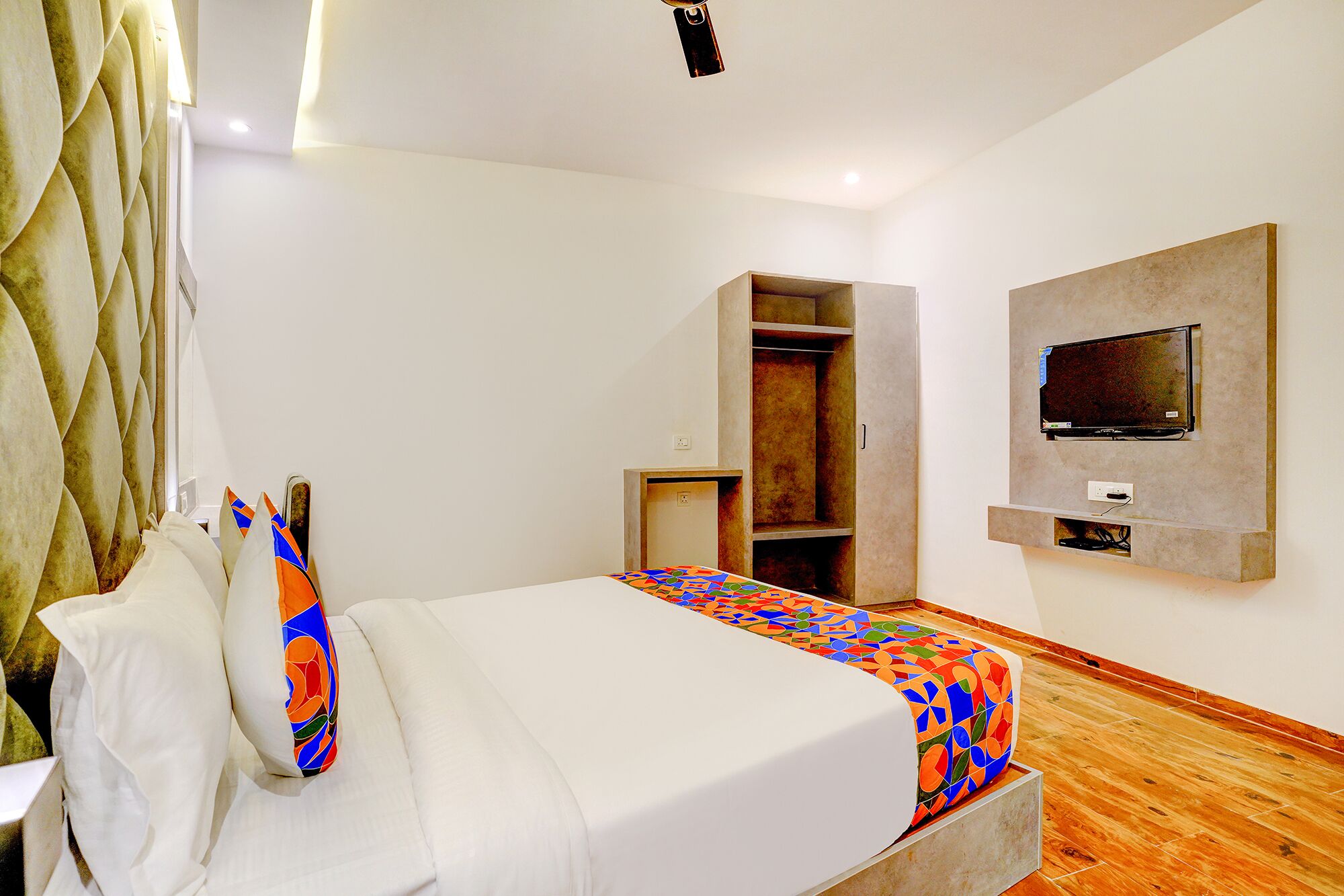 A hotel room with a bed, a TV mounted on the wall, and a wardrobe.
