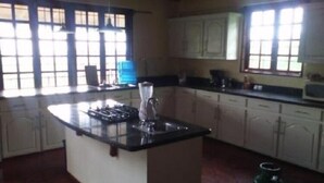 A kitchen with a central island, white cabinets, and a large window providing natural light. - Romantic 1 Bedroom Splendora (Gros Islet)