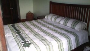 A bed with a striped bedspread and pillows, a wooden headboard, and a nightstand with a lamp. - Romantic 1 Bedroom Splendora (Gros Islet)