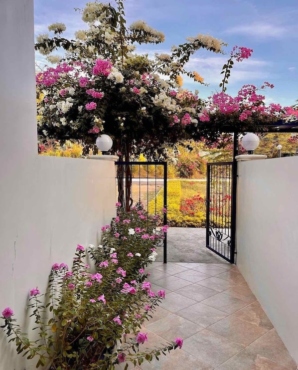A covered outdoor area with a tiled floor and a black metal gate.