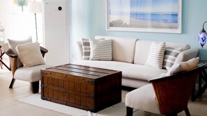 A living room with a sofa, armchairs, a wooden coffee table, and a framed picture on the wall. - Trillo Bay Villas (Morong)