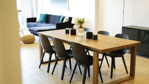 A modern dining area with a wooden table and black chairs, a small potted plant, and a blue sofa in the background. - Trillo Bay Villas (Morong)
