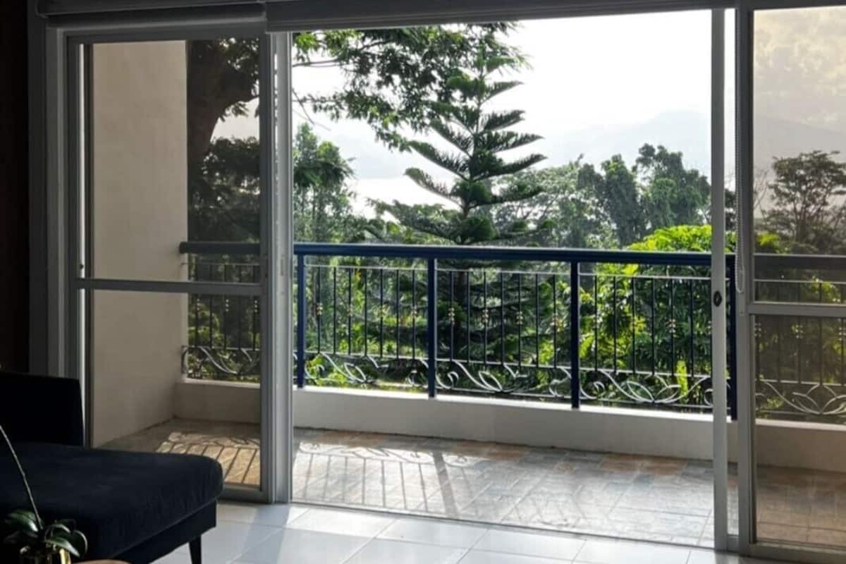 A spacious balcony with a view of lush greenery and trees.
