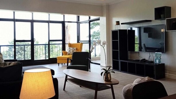 A spacious living room with a large TV, comfortable seating, and a balcony view. - Trillo Bay Villas (Morong)