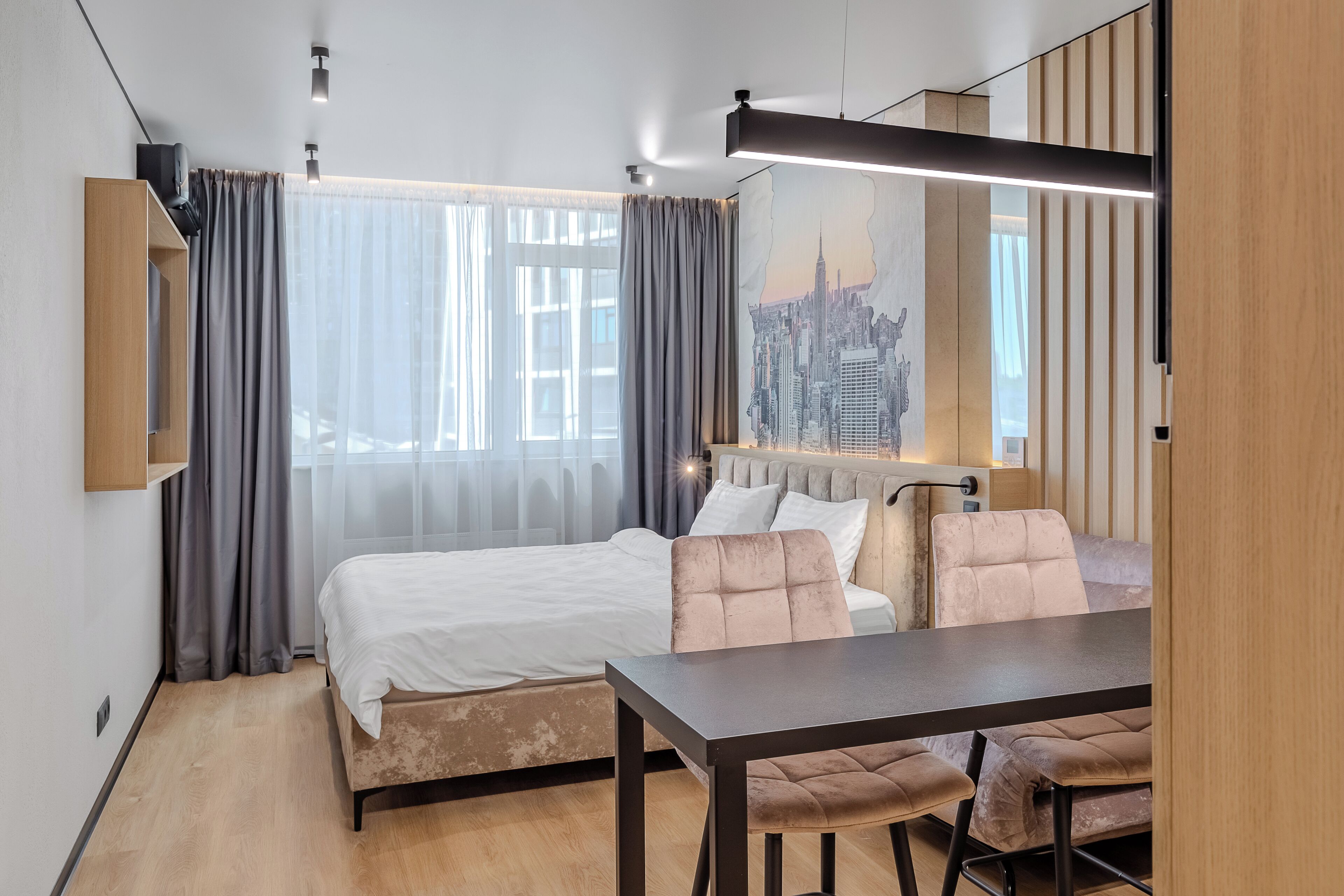 Ein modernes Hotelzimmer mit Bett, Esstisch und Blick auf die Stadt.