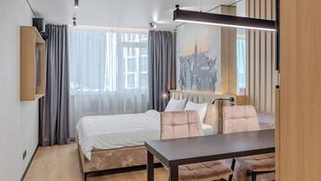 Ein modernes Hotelzimmer mit Bett, Esstisch und Blick auf die Stadt.
