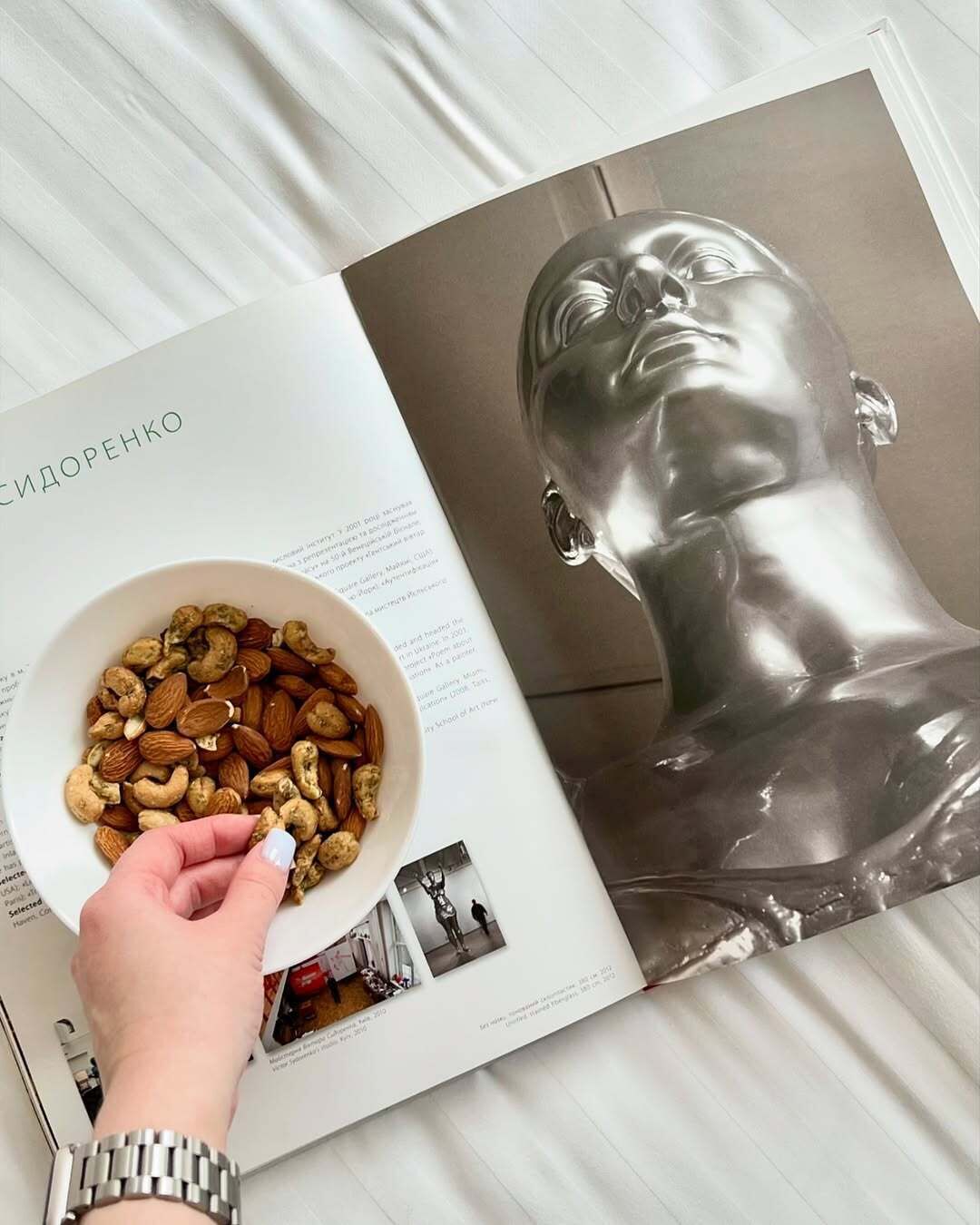 Un libro con una escultura metálica y un cuenco de nueces.
