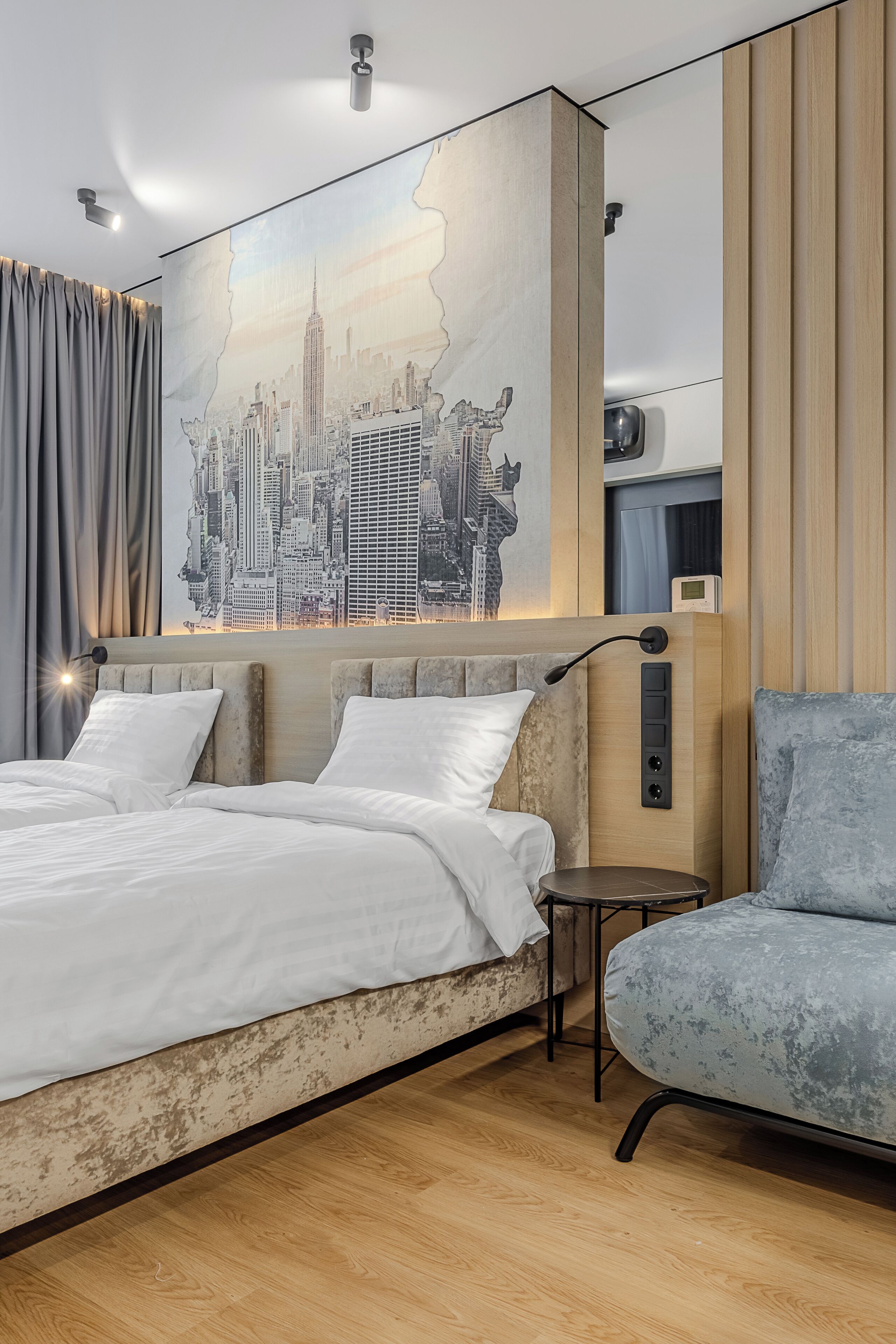 Een moderne hotelkamer met een groot bed, een zithoek en een stadsgezichtsmural op de muur.