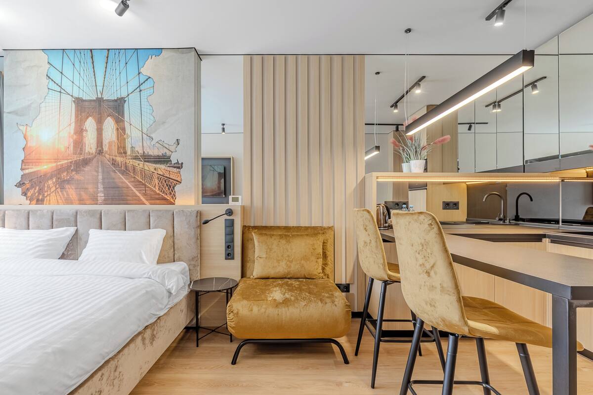 Ein modernes Hotelzimmer mit einem großen Bett, einem Schreibtisch mit zwei Stühlen, einem Wandgemälde einer Brücke und einer Wandverkleidung aus Holz.