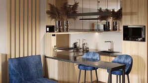 A modern kitchen with a central island, bar stools, and a blue chair. - Manhattan High Line Apart (Kyiv)