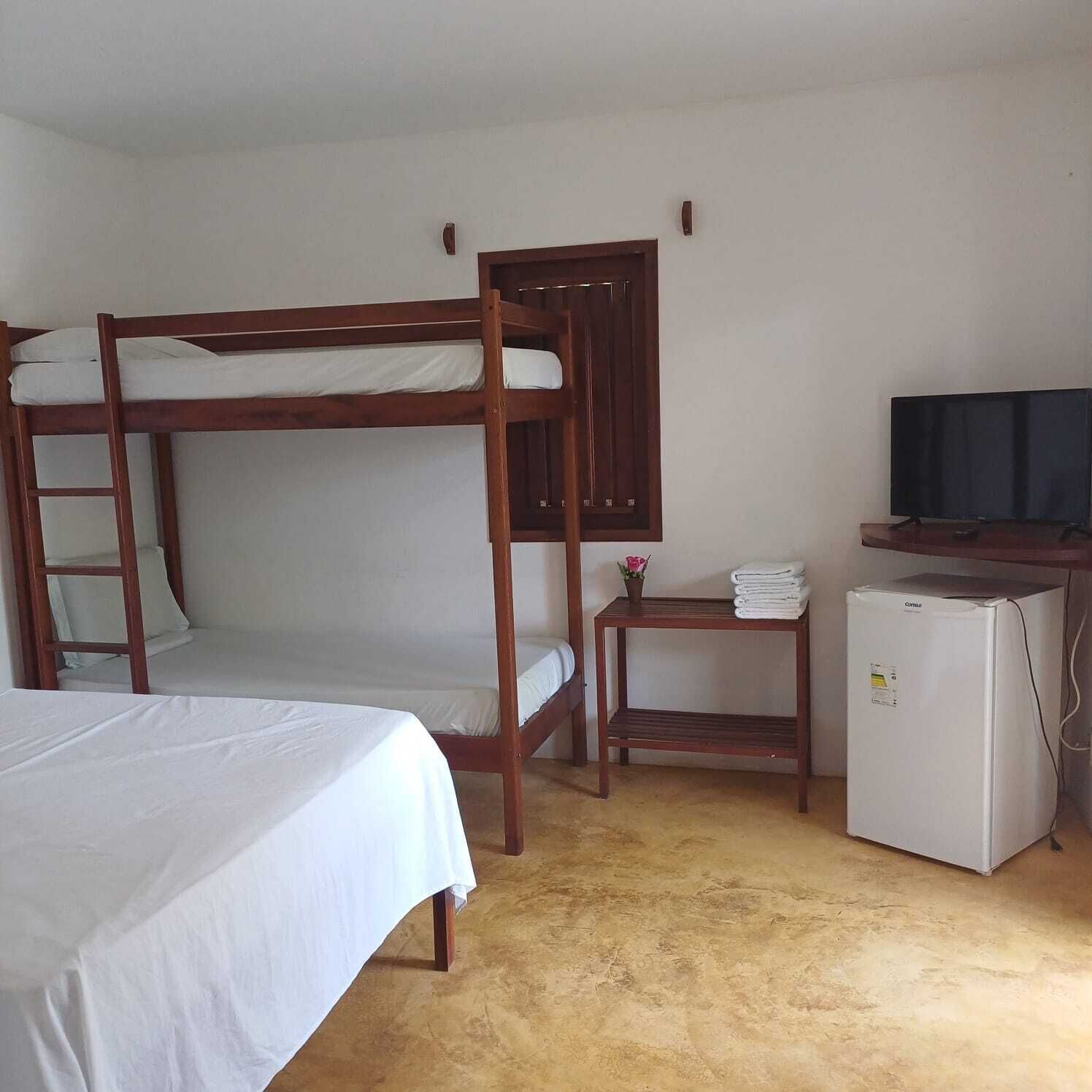 A room with bunk beds, a small table with a TV, and a refrigerator.